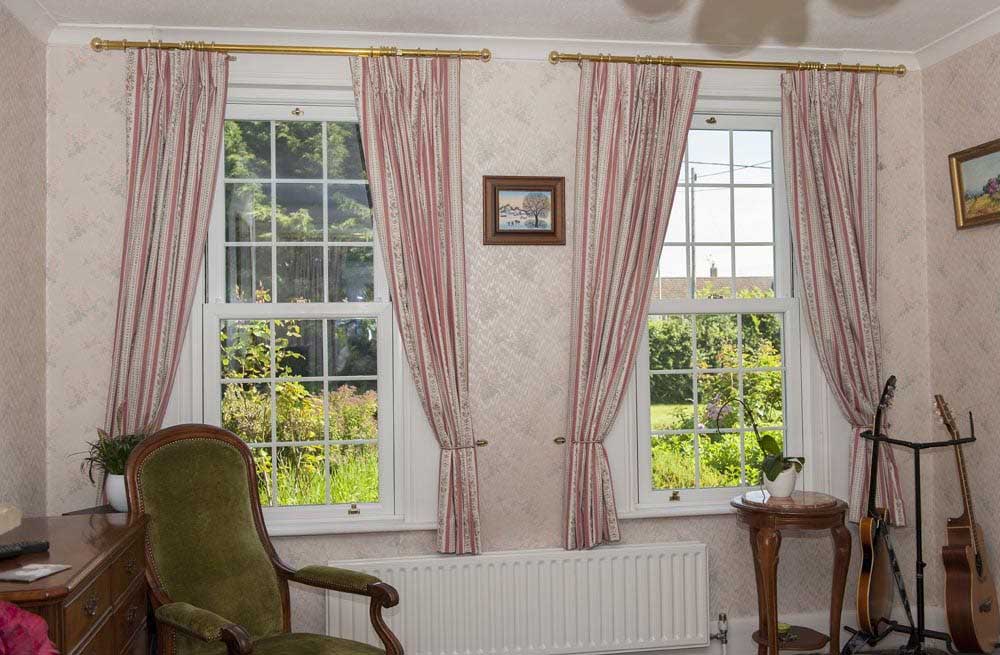 two closed georgian upvc sash windows in a living room with pink curtains in doncaster